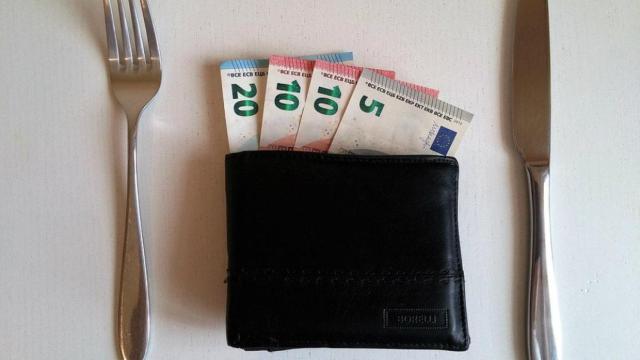 Una cartera con dinera entre cubiertos en una imagen de archivo /Creative Commons influencer