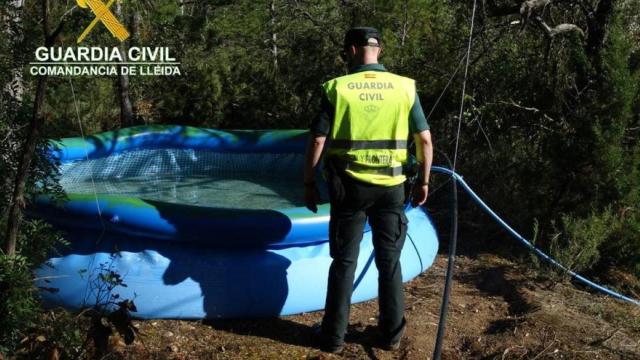 Un agente de la Guardia Civil frente a una de las piscinas usadas para embalsar el agua / GUARDIA CIVIL