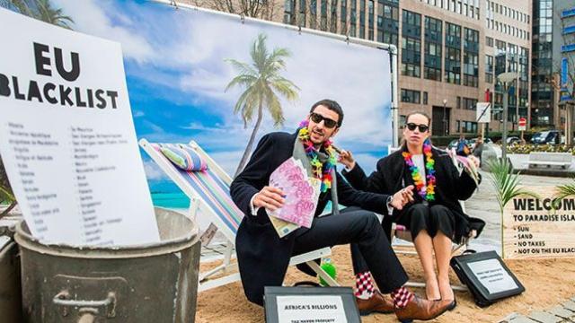 Dos activistas protestan contra la 'lista negra' de paraísos fiscales elaborada por la UE ante el Consejo Europeo en Bruselas / EFE