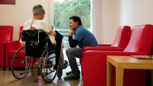 Un voluntario del programa de 'la Caixa' da ánimos a un paciente / CG