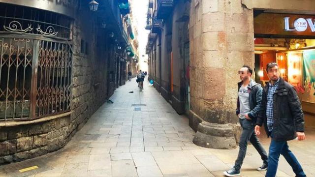 Dos personas pasando por el chaflán donde el narco Chan S. ha instalado un narcopiso en el Barrio Gótico / CG