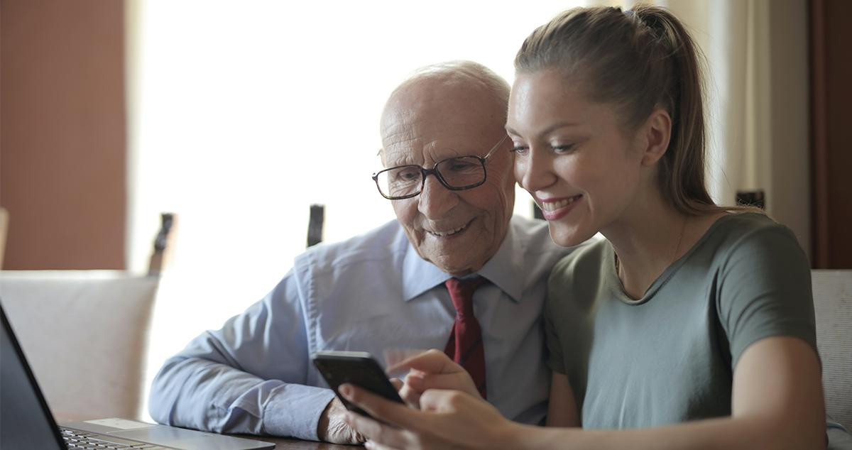 Una chica enseña a su abuelo a usar un teléfono móvil / PEXELS