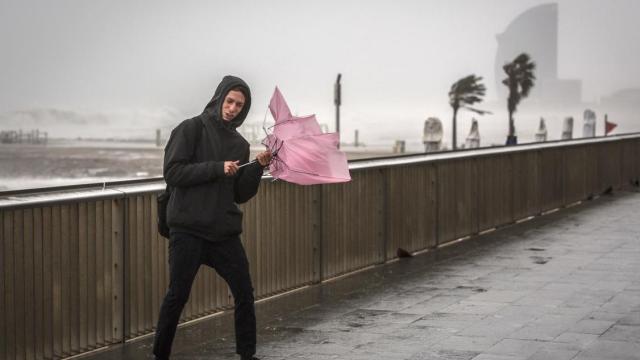Un joven sujeta un paraguas ante las fuertes ráfagas de viento que se prevén este fin de semana