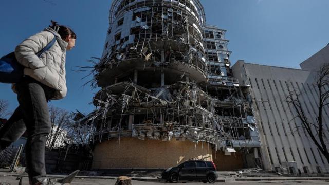 Una mujer camina ante un edificio seriamente dañado por los bombardeos que sufre la ciudad de Jarkiv, en el punto de mira de Moscú / MANUEL BRUQUE - EFE