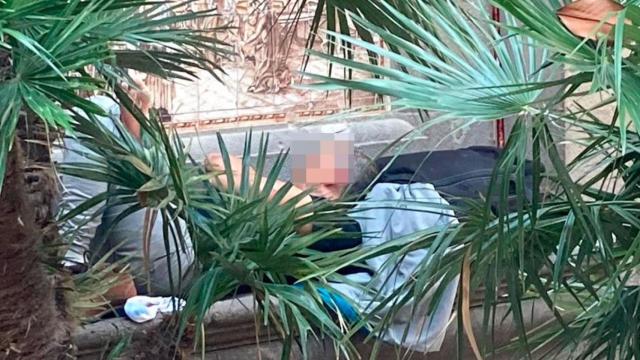 Un persona sintecho duerme en un banco del centro de Barcelona / ELENA BURÉS