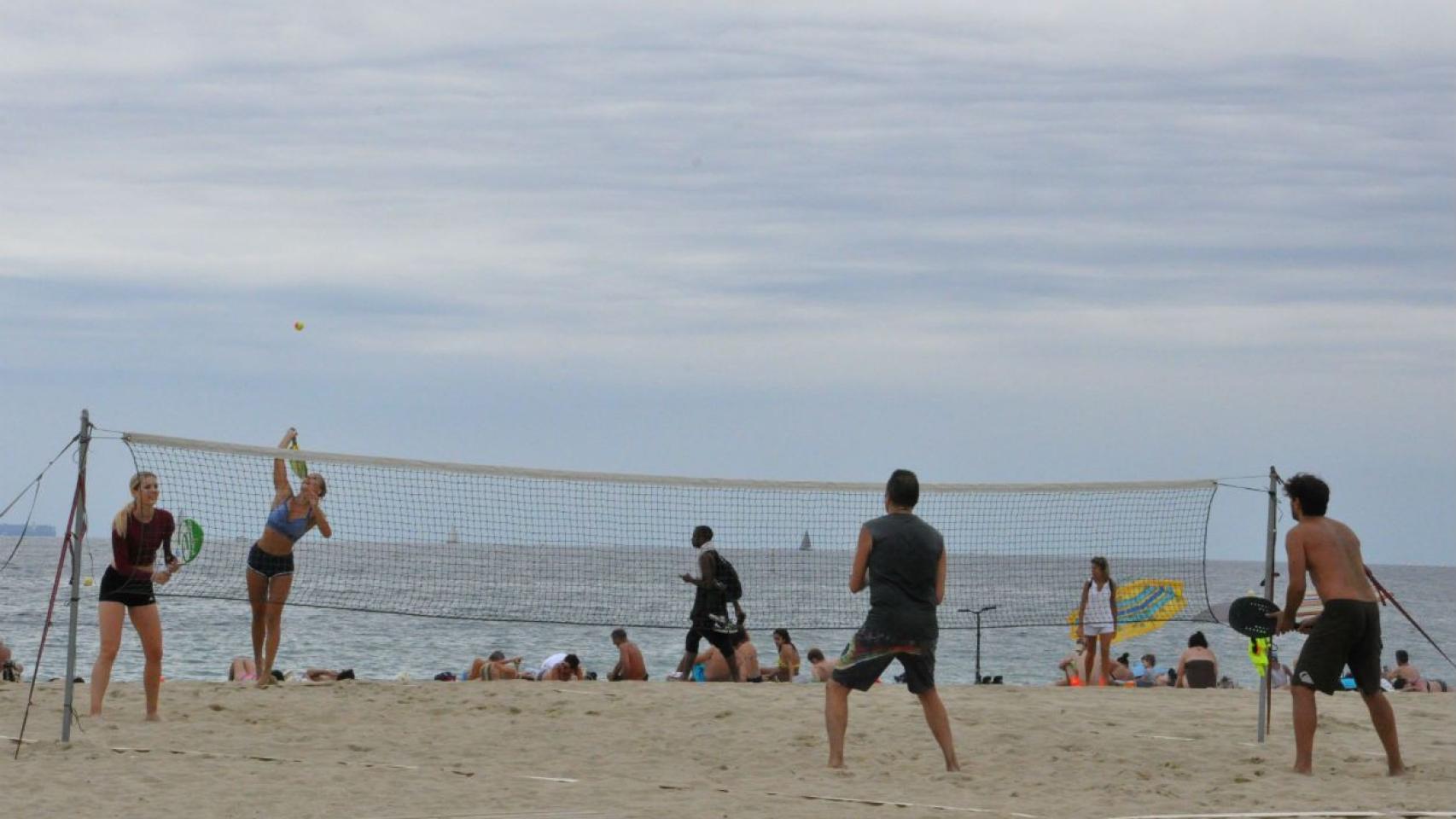 Dos parejas, una de chicas y otra de chicos, practicando tenis playa en el Beach Tennis Barcelona / MIKI