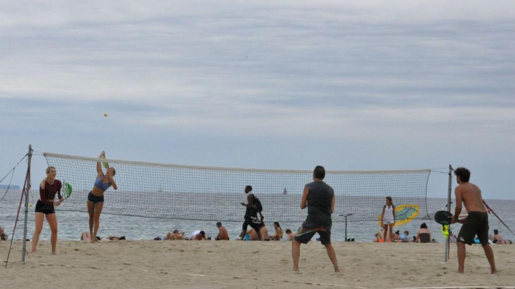 Dos parejas, una de chicas y otra de chicos, practicando tenis playa en el Beach Tennis Barcelona / MIKI