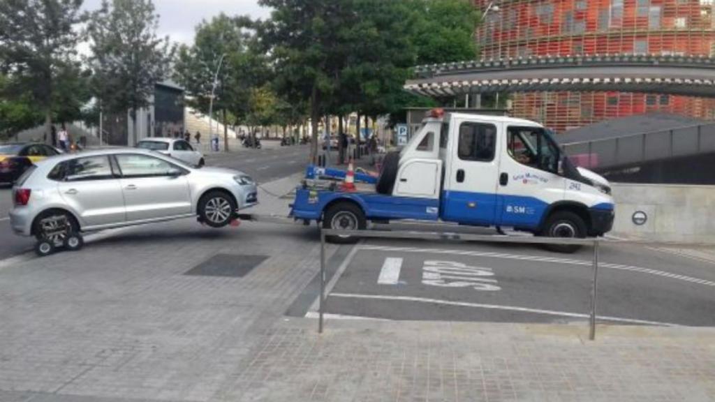 Una grúa municipal entra con un coche enganchado en el depósito de Glòries / JORDI SUBIRANA