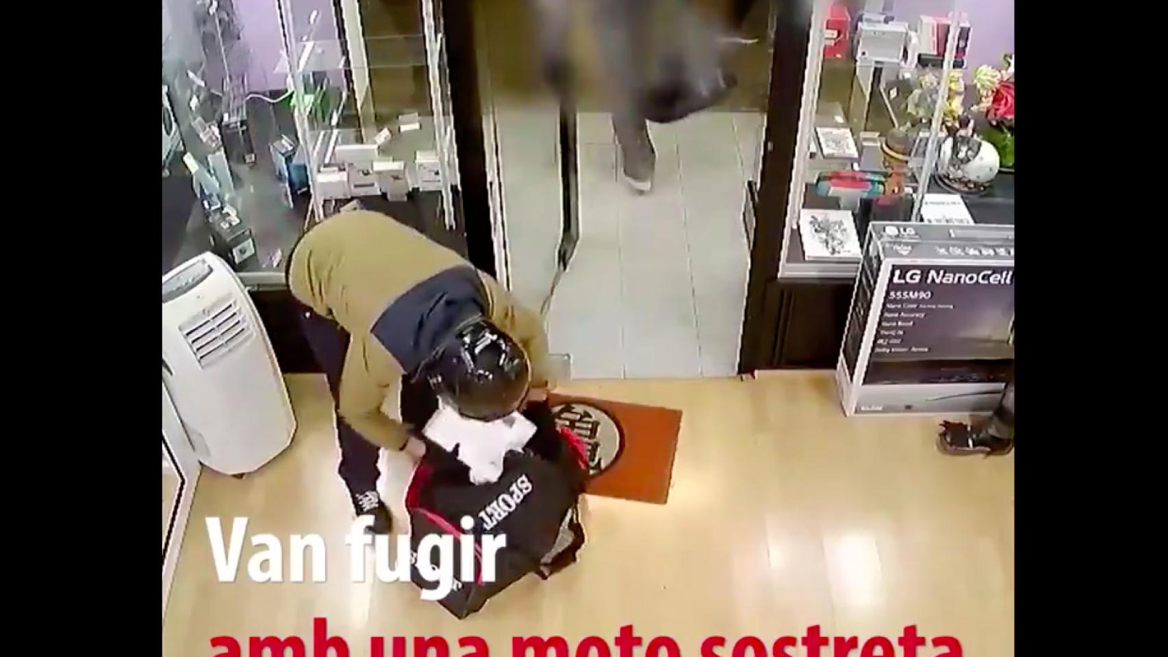 Uno de los atracadores introduce móviles robados en una bolsa / MOSSOS D'ESQUADRA