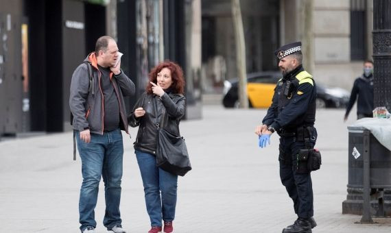 Un agente de la Guardia Urbana verifica que se cumpla el confinamiento y las excepciones al mismo / EFE