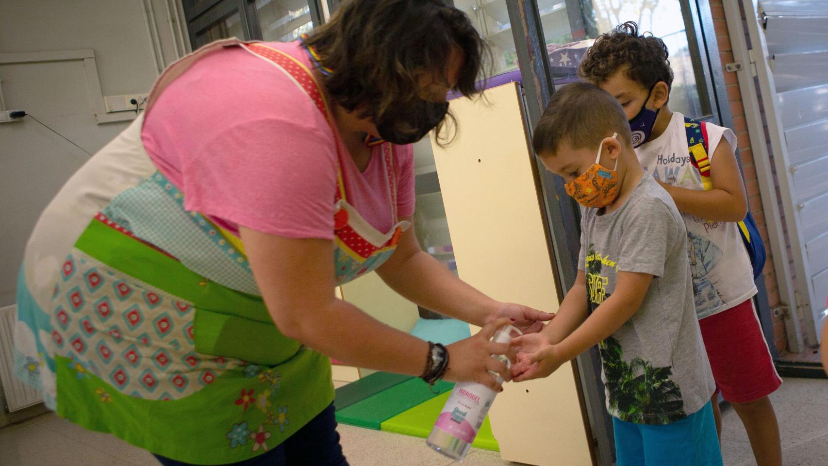 Una docente de la Escuela Catalonia de Barcelona aplica gel hidroalcohólico a sus alumnos al entrar al recinto / EFE