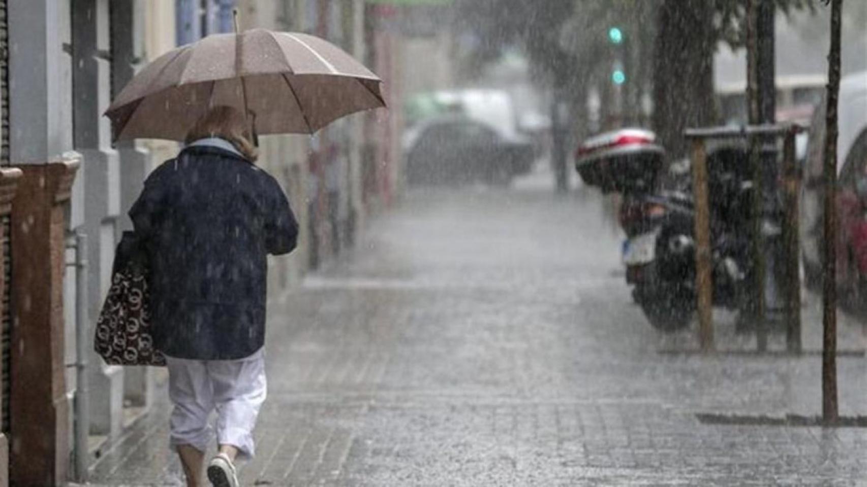 Una mujer se protege de la lluvia con un paraguas / EFE
