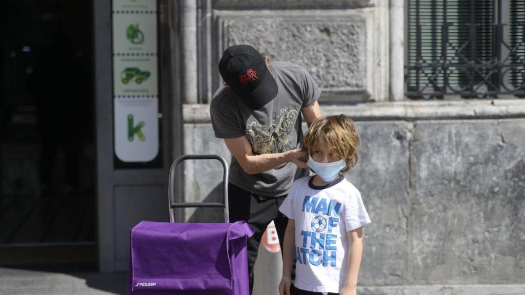 Un padre coloca la mascarilla a su hijo / EFE