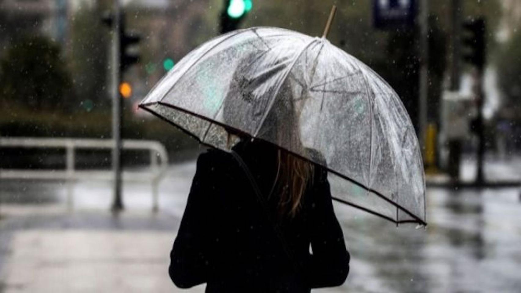 Una mujer se protege del frío y la lluvia con un paraguas / EFE