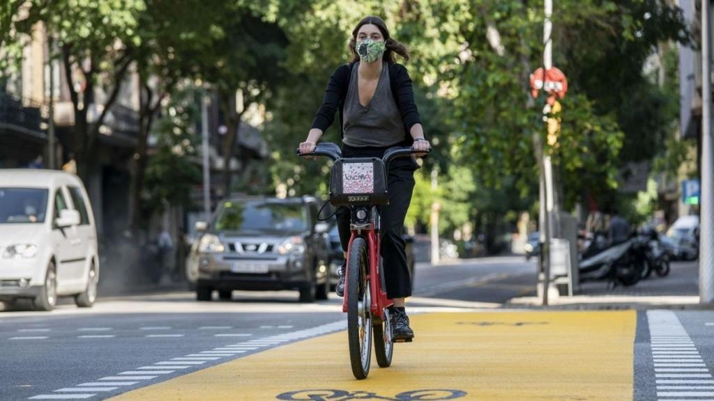 Una ciclista con mascarilla en Bicing por la calle de Pau Claris / AYUNTAMIENTO DE BARCELONA