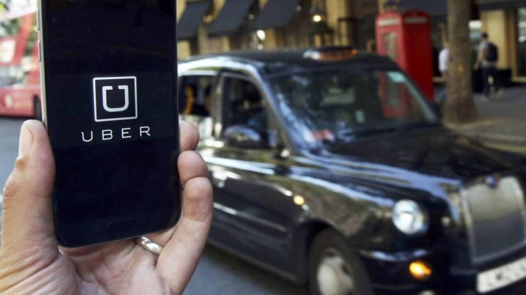 Imagen de archivo de un teléfono con el logotipo de Uber y un VTC en el fond