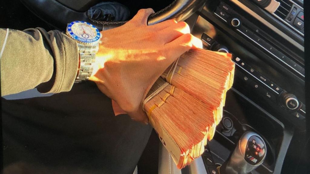 Un miembro del clan de Los Manolos sostiene un fajo de billetes