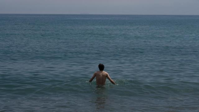 Un hombre se da un baño en la playa de la Barceloneta