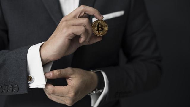 Hombre de negocios sostiene un Bitcoin
