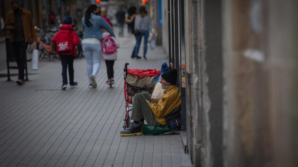 Una persona sin techo permanece en el suelo de una calle cercana al Hospital de campaña instalado en la parroquia de Santa Anna, en Barcelona, Cataluña, (España)