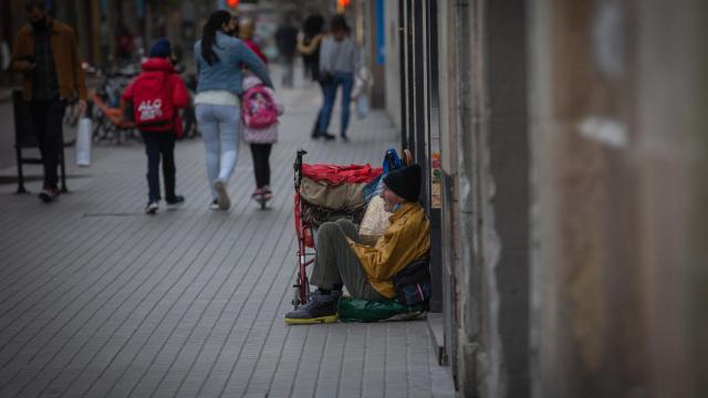 Una persona sin techo permanece en el suelo de una calle cercana al Hospital de campaña instalado en la parroquia de Santa Anna, en Barcelona, Cataluña, (España), a 14 de noviembre de 2020