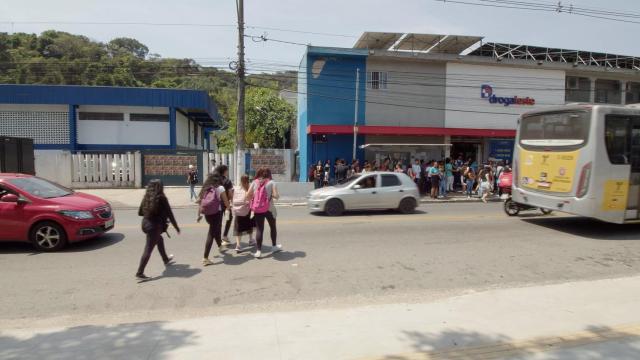 Unos niños cruzan la calle entre vehículos para ir al colegio