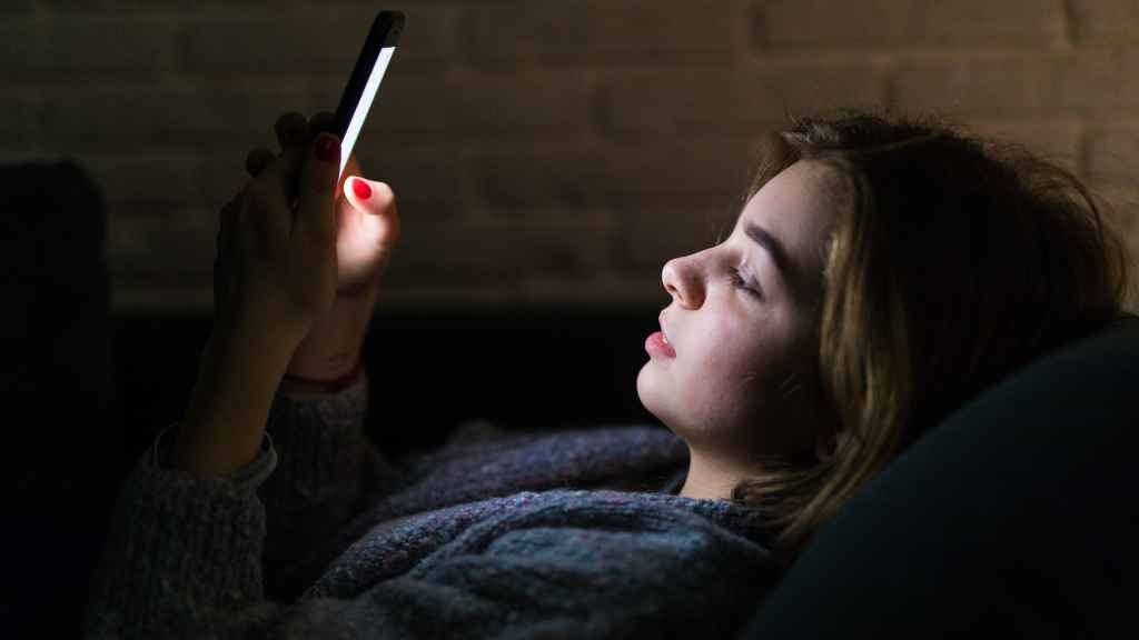 Una mujer joven mira el teléfono móvil