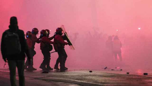 Varios agentes de la Ertzaintza se protegen ante el lanzamiento de objetos en la entrada del estadio San Mamés