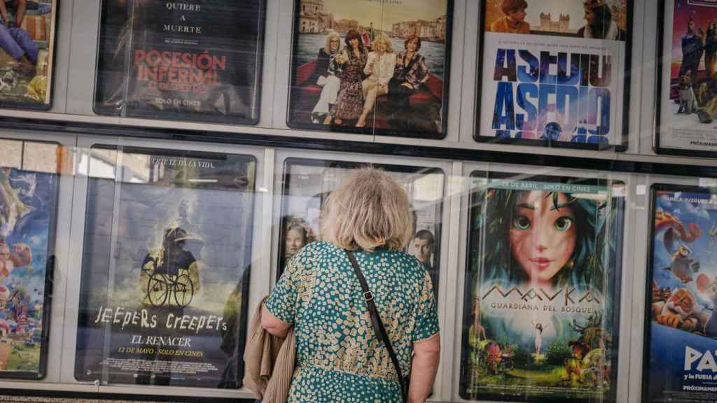 Una persona mayor mira la cartelera de un cine