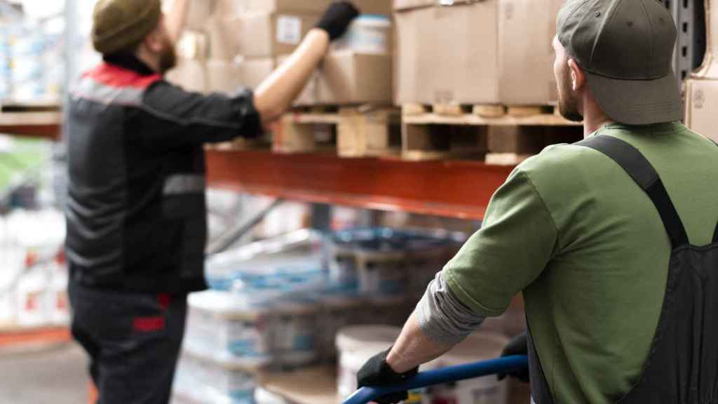 Dos trabajadores descargan material en un almacén