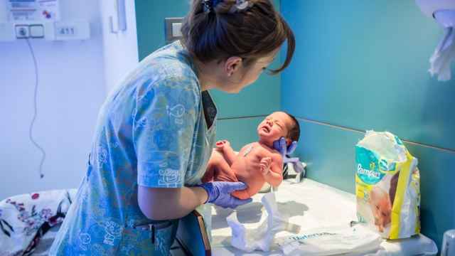 Una matrona sujeta un bebé recién nacido