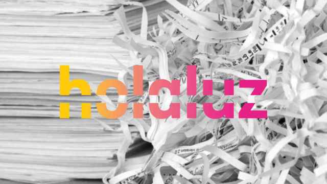 Logotipo de Holaluz encima de papeles triturados