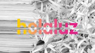 Logotipo de Holaluz encima de papeles triturados