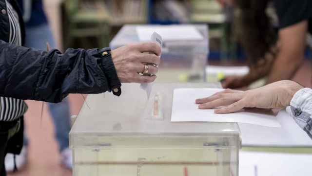 Una persona mete su voto en la urna en un colegio electoral