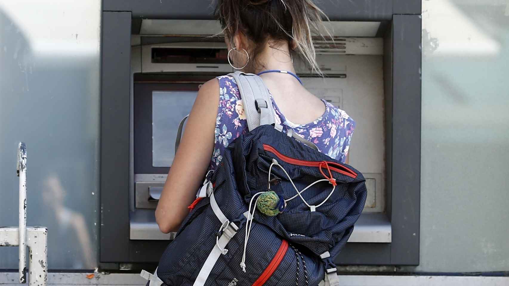 Una joven saca dinero de un cajero automático