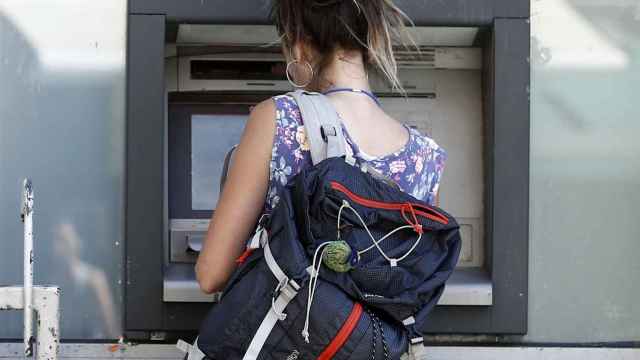 Una joven saca dinero de un cajero automático