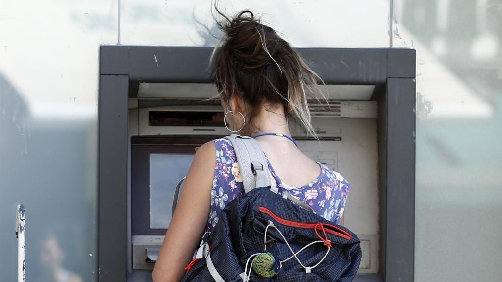 Una joven saca dinero de un cajero automático