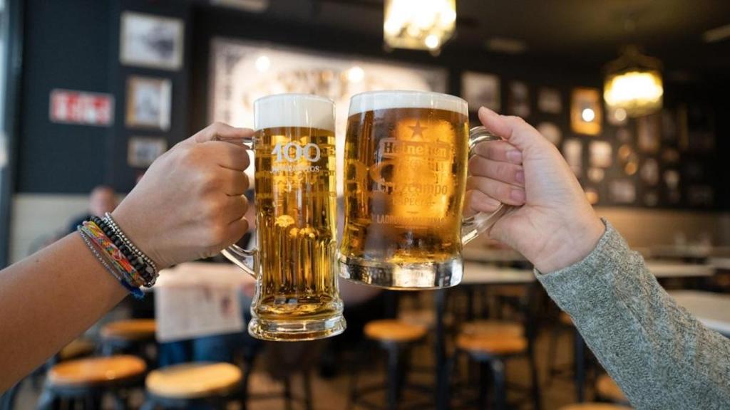 Dos personas brindando con cerveza en un bar | RESTALIA