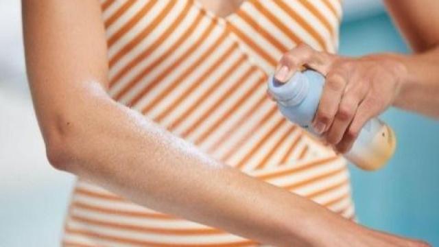 Una mujer se aplica protector solar