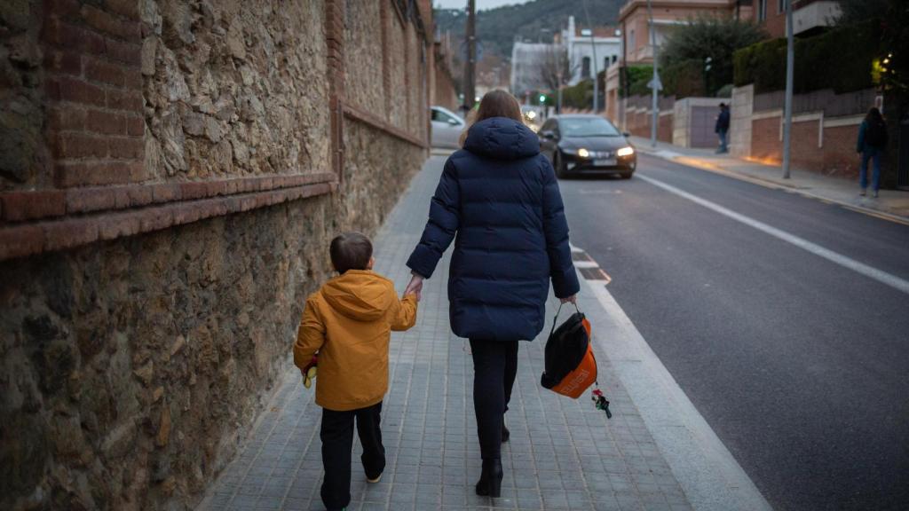Una mujer lleva de la mano a un niño a clase, en una imagen de archivo