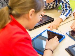 Imagen de archivo de varios niños usando tablets en un centro escolar