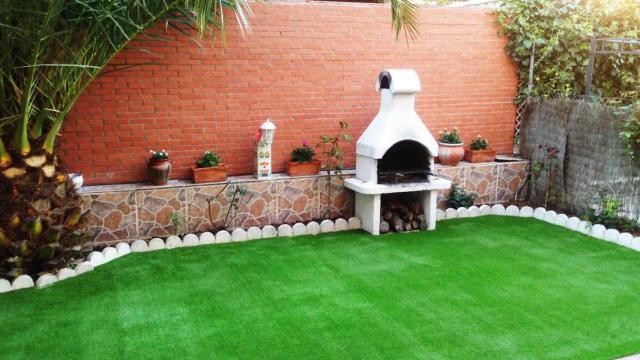 Césped artificial en un jardín con barbacoa