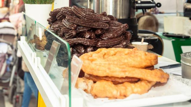 Churros clásicos y recubiertos de chocolate en el estante de un establecimiento