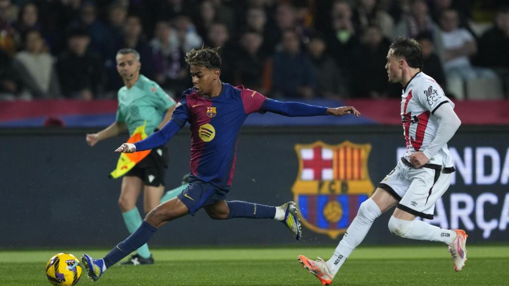 Lamine Yamal golpea el balón, defendido por Pep Chavarría durante el Barça-Rayo