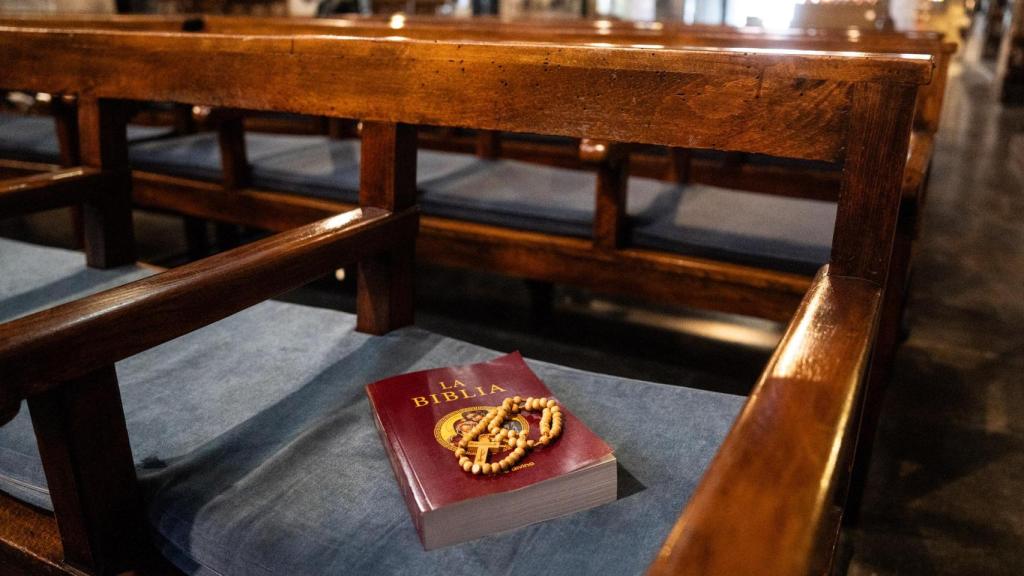 Una Biblia y un rosario sobre un asiento en una iglesia