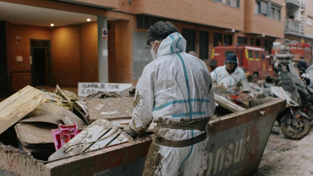 Voluntarios retiran escombros en una calle asolada por la DANA
