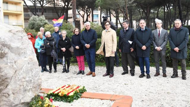 El presidente de la Generalitat, Salvador Illa (c), y el conseller de Justícia i Qualitat Democràtica, Ramon Espalader (3d), durante su visita al monolito del homenaje a los refugiados del campo de concentración de Argèles-sur-mer, a 7 de marzo de 2025