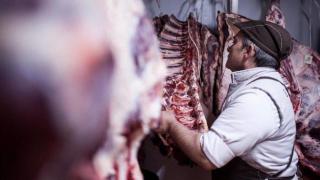 Imagen del operario de una cárnica tratando una pieza