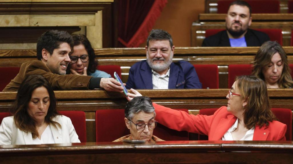 El portavoz del grupo parlamentario de los Comuns, David Cid (i) muestra su móvil a la consellera de Territorio, Vivienda y Transición Ecológica de la Generalitat, Sílvia Paneque (d), durante la sesión de control en el pleno del Parlament, celebrada este miércoles después de que el pasado lunes, el President anunciara un plan para movilizar 1.500 millones de euros en ayudas y préstamos para hacer frente al impacto de la subida de aranceles de Estados Unidos