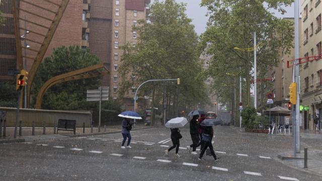 Varias personas caminan por Barcelona con paraguas bajo una tormenta